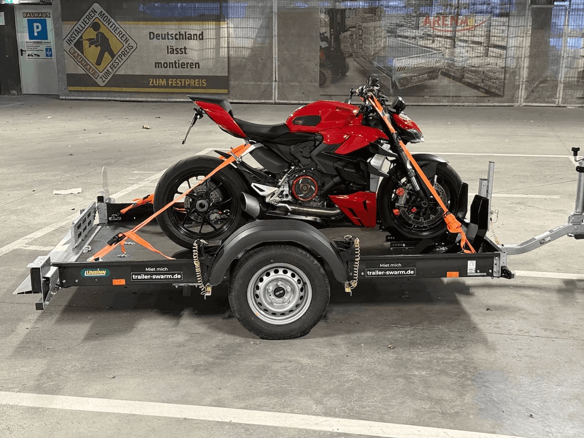 Hochgekippter Unsinn-Anhänger mit verzurrter Ducati Streetfighter, fahrbereit abgestellt in der Tiefgarage